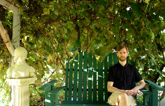 Peter Dzialo sitting under a grape arbor.